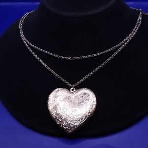 Heart locket necklace with an etched floral pattern.